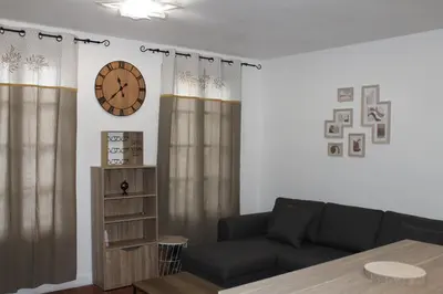 a living room with a couch and a clock on the wall at Bel Appartement T2 in Carcassonne