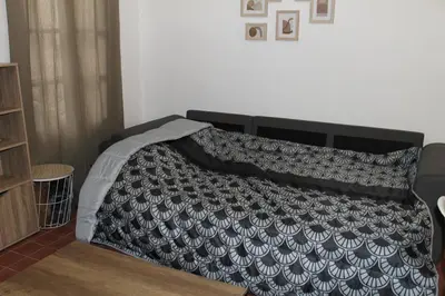 a bed with a black and white blanket on it at Bel Appartement T2 in Carcassonne