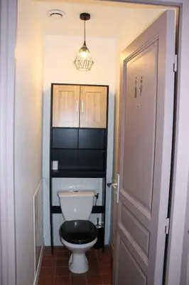 a bathroom with a toilet with a black seat at Bel Appartement T2 in Carcassonne