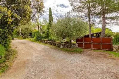 a dirt road with a red fence and trees at Chez Claudie et Jacques in Ventenac-Cabardès
