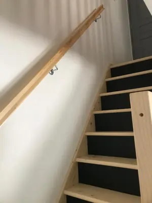 a stairwell with wooden risers and a white wall at Petite maison in Carcassonne