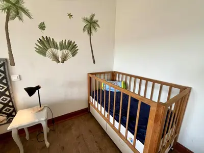 a nursery with a crib and palm trees on the wall at Le gîte du Clos d'André in Castelnaudary