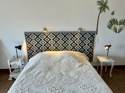 a bedroom with a bed with a black and white headboard at Le gîte du Clos d'André in Castelnaudary