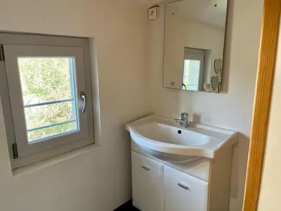 a bathroom with a sink and a mirror and a window at Le gîte du Clos d'André in Castelnaudary