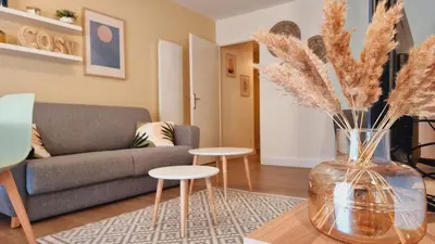 a living room with a couch and a vase with flowers at T2 quartier Mermoz, 2 places de parking privées in Pamiers