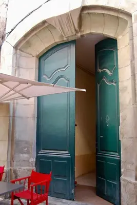 a green door with two red chairs in front of it at Appartement avec terrasse centre de la Bastide in Carcassonne