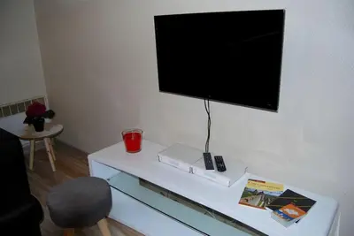 a tv on a wall with a table with a remote control at Appartement avec terrasse centre de la Bastide in Carcassonne