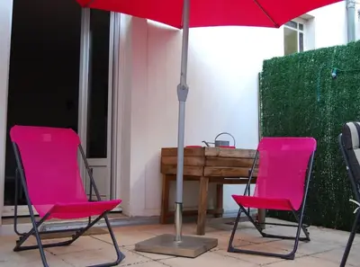 two pink chairs and a table with an umbrella at Appartement avec terrasse centre de la Bastide in Carcassonne