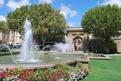 a fountain in a park with flowers in front of a building at Appartement avec terrasse centre de la Bastide in Carcassonne