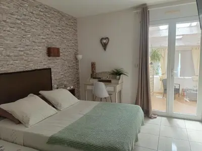 a bedroom with a bed and a table and a balcony at Les oliviers Puisserguier in Puisserguier
