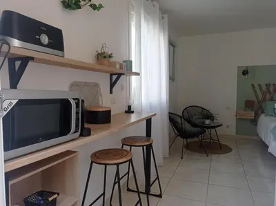 a living room with a tv on a counter with stools at Les oliviers Puisserguier in Puisserguier