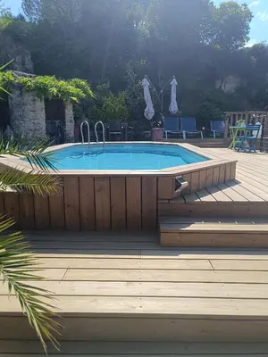 a swimming pool on a wooden deck with a wooden deck at Les oliviers Puisserguier in Puisserguier