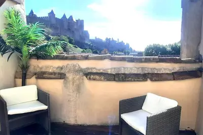 two chairs sitting next to a wall with a castle at Emplacement N°1+Terrasse Vue+Cité+Trivalle+clim in Carcassonne