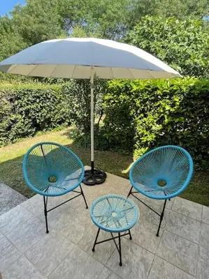 two blue chairs and an umbrella on a patio at Chez Francis & Valérie in Villegailhenc