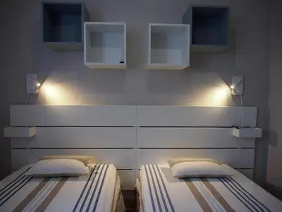 two twin beds in a bedroom with lights on the wall at Chez Francis & Valérie in Villegailhenc