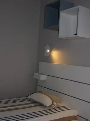 a bedroom with a bed with a white wall at Chez Francis & Valérie in Villegailhenc