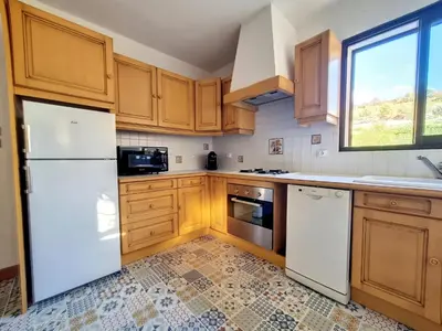 a kitchen with wooden cabinets and a white refrigerator at Maison sur la place du marché à St Chinian in Saint-Chinian