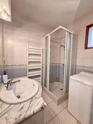 a white bathroom with a sink and a shower at Maison sur la place du marché à St Chinian in Saint-Chinian