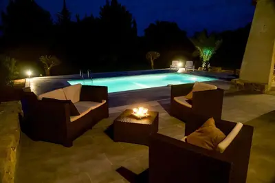 a pool with two chairs and a table with a candle at villa queen-south IT in Ventenac-Cabardès
