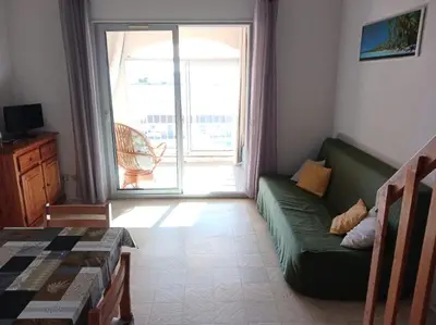 a living room with a green couch in front of a door at Appartement avec magnifique vue sur mer in Gruissan
