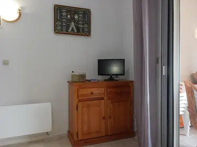 a television sitting on top of a wooden cabinet at Appartement avec magnifique vue sur mer in Gruissan
