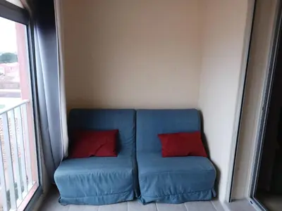 a blue couch with two red pillows in a room at Appartement avec magnifique vue sur mer in Gruissan