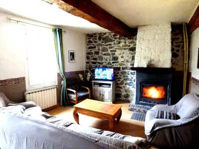 a living room with a stone fireplace and a couch at Gîte Les Mimosas in Prugnanes