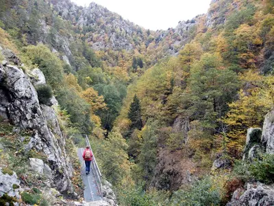 a person walking across a suspension bridge over a canyon at Gîte Les Mimosas in Prugnanes