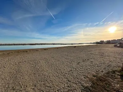 a sandy beach with the sun in the sky at VILLA DU PIN in Gruissan