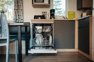 a dishwasher with dishes in it in a kitchen at Mobil Home XXL 4 chambres - Camping Tarn - Domaine du Koukano in Maurens-Scopont