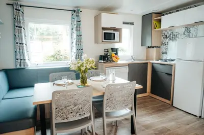 a kitchen and dining room with a table and chairs at Mobil Home XXL 4 chambres - Camping Tarn - Domaine du Koukano in Maurens-Scopont
