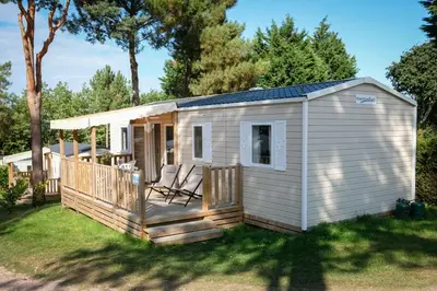 a small white shed with two chairs on a deck at Mobil Home XXL 4 chambres - Camping Tarn - Domaine du Koukano in Maurens-Scopont