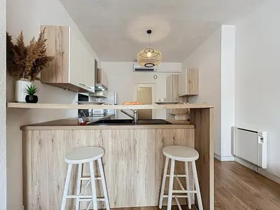 a kitchen with two stools at a wooden counter at Le Cocon - Wifi - Cour privative - Proche Halles in Narbonne
