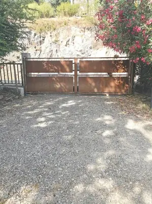 a wooden gate with a bush with pink flowers at Le Moulin du plô du Roy in Villeneuve-Minervois