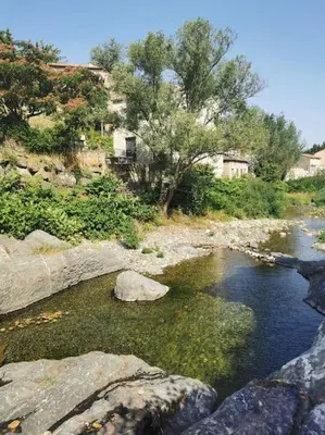 a stream of water with rocks and trees and houses at Le Moulin du plô du Roy in Villeneuve-Minervois