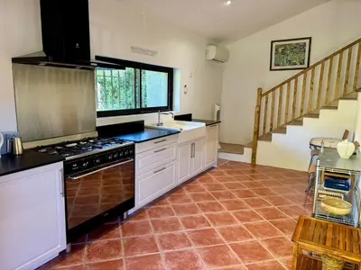 a kitchen with a stove top oven next to a staircase at Maison Tulipe in Puivert