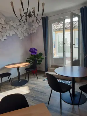 a room with tables and chairs and a window at Face Cité - Chambres D'Hôtes - Parking & Garage Gratuit - Wi-Fi Gratuit in Carcassonne