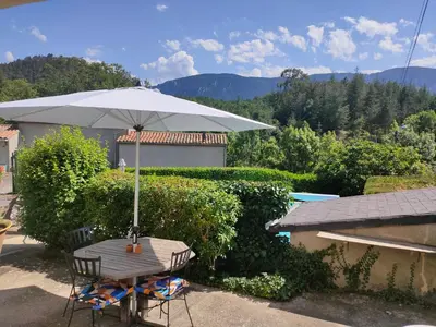 a table and chair with an umbrella and a pool at Coste de Laval in Quillan