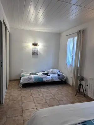 a bedroom with two beds and a light on the wall at Appartement spacieux de plein pied avec 2 chambres, cuisine, salon, terrasse à 2 minutes de la plage in Gruissan