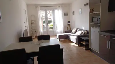 a living room with a table and a couch at Appartement spacieux de plein pied avec 2 chambres, cuisine, salon, terrasse à 2 minutes de la plage in Gruissan