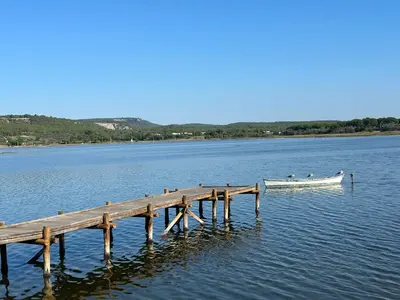 a boat on the water next to a dock at Appartement spacieux de plein pied avec 2 chambres, cuisine, salon, terrasse à 2 minutes de la plage in Gruissan