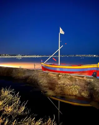 a boat sitting on the beach at night at Appartement spacieux de plein pied avec 2 chambres, cuisine, salon, terrasse à 2 minutes de la plage in Gruissan