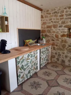 a kitchen with a counter and a stone wall at Amé-lys in Véraza