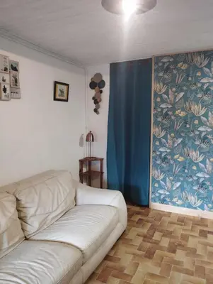 a living room with a white couch and a blue curtain at Amé-lys in Véraza