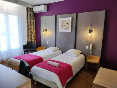 two beds in a hotel room with purple walls at Hôtel et Appart'Hôtel Le Relais Du Val D'Orbieu in Ornaisons