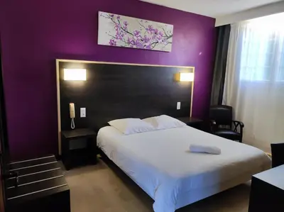 a bedroom with a large bed with a purple wall at Hôtel et Appart'Hôtel Le Relais Du Val D'Orbieu in Ornaisons