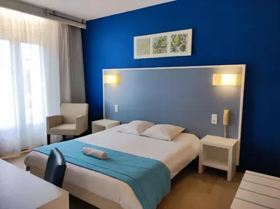 a blue bedroom with a bed and a blue wall at Hôtel et Appart'Hôtel Le Relais Du Val D'Orbieu in Ornaisons