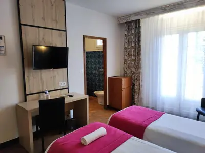 a hotel room with two beds and a desk and a television at Hôtel et Appart'Hôtel Le Relais Du Val D'Orbieu in Ornaisons