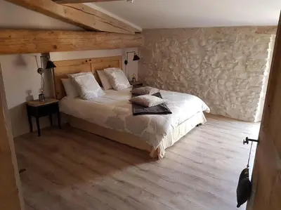 a bedroom with a bed and a wooden floor at Le gîte Joyeuse triplette Limoux Carcassonne in Limoux
