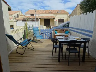a patio with chairs and a table on a deck at Maison près des plages in Port-la-Nouvelle